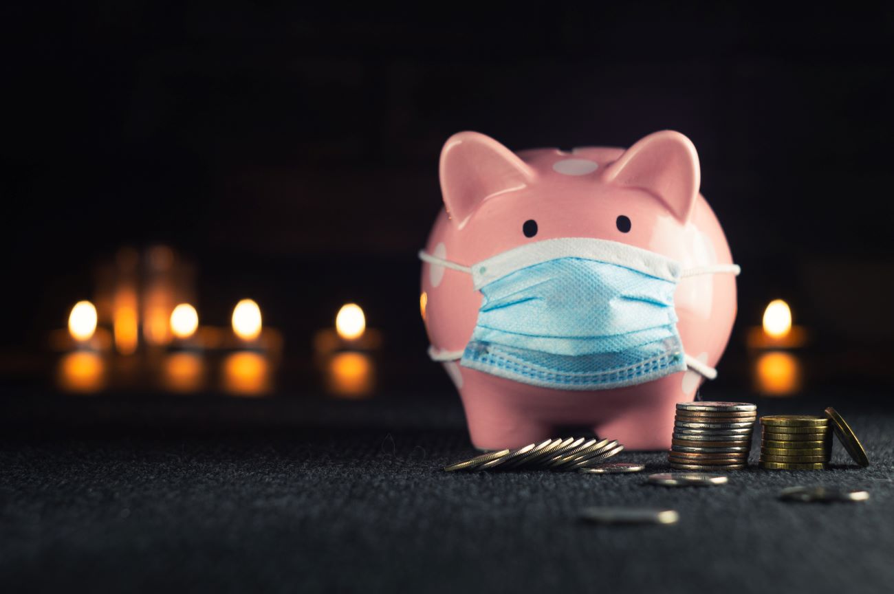 Classic Piggy Bank with a medical mask on a dark background.